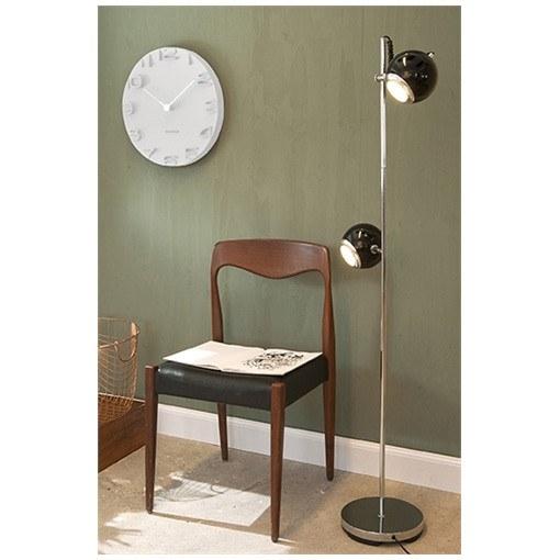 A Karlsson On The Edge Wall Clock - White (42cm) and a chair in front of a green wall with a unique feature.