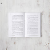 A motivational copy of "101 Essays That Will Change The Way You Think" by Brianna Wiest, published by Thought Catalog, featuring an open page on a wooden surface.