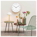 A minimal Karlsson Lofty Wall Clock - White (40cm) on a table next to a green vase.