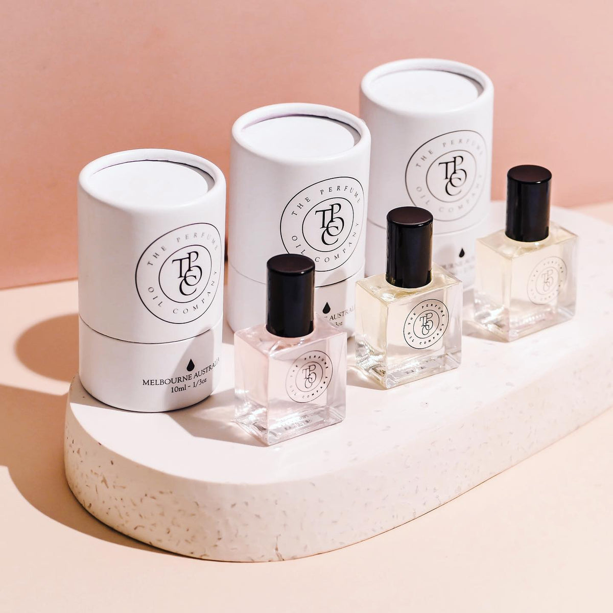 Three bottles of NUDE, inspired by Beige (CC) perfume sitting on top of a pedestal. (Brand: The Perfume Oil Company)