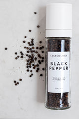 A jar of Tasteology Black Pepper on a marble countertop.