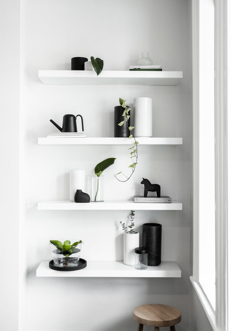 A white Zakkia shelf with Bulb Vase Orb - Frost, handmade blown glass vases in black and white, creating a statement piece.