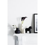 A Carved Vase Curved - Confetti mantle adorned with black Zakkia vases and a framed picture.