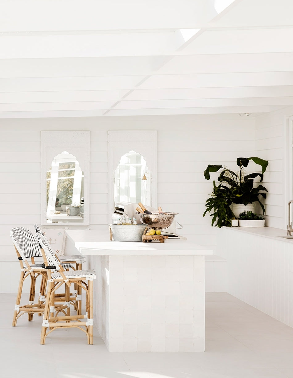 White kitchen island with rattan stools and arched windows