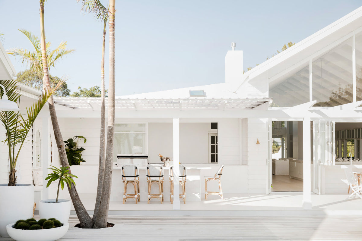White coastal house with a timber deck and palm trees