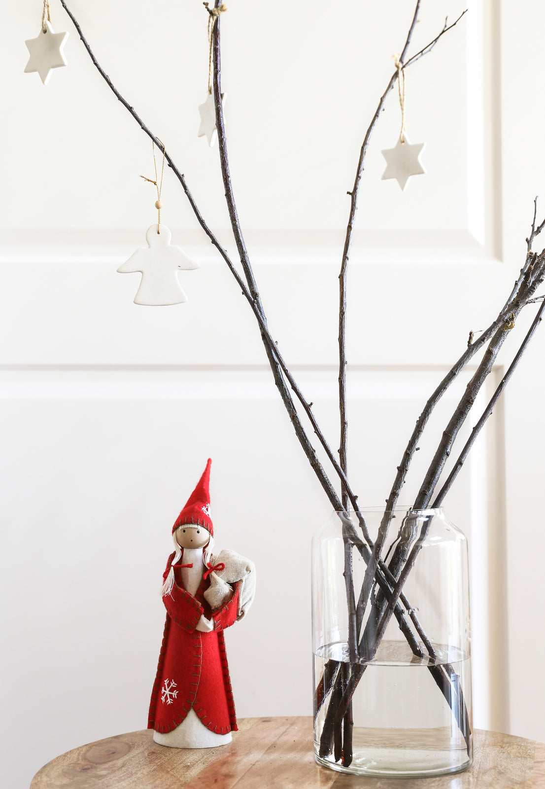 A handmade blown glass Christmas tree adorned with twigs and ornaments, elegantly displayed in a Zakkia tall clear Deco Vase.