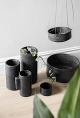 A group of Zakkia Embers Table Planter - Small Charred black pots and vases with an organic finish on a wooden floor.