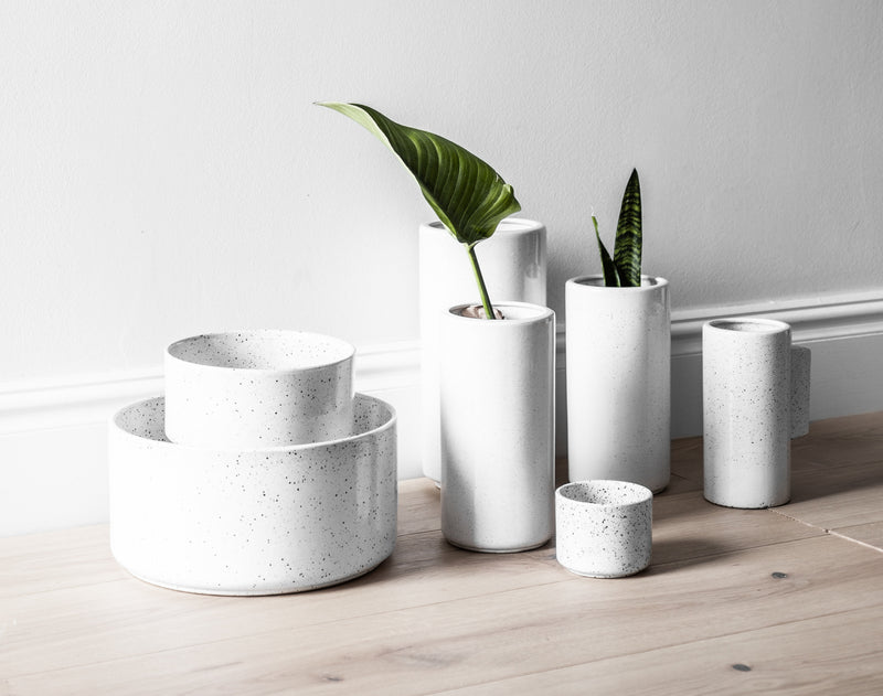 A group of white ZAKKIA Embers Hanging Planter - Small Charred vases and a plant on a wooden floor.