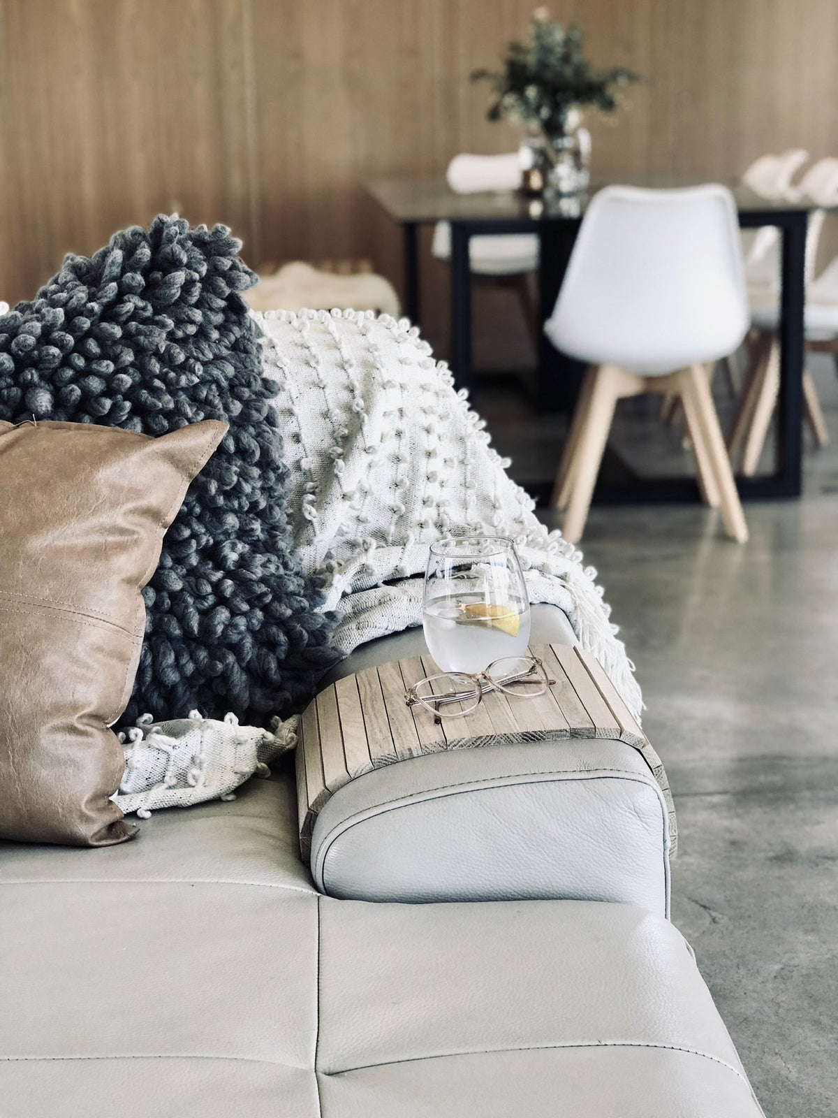 Ned Collections armchair side rest tray on a sofa arm holding a glass of wine, with cushions alongside