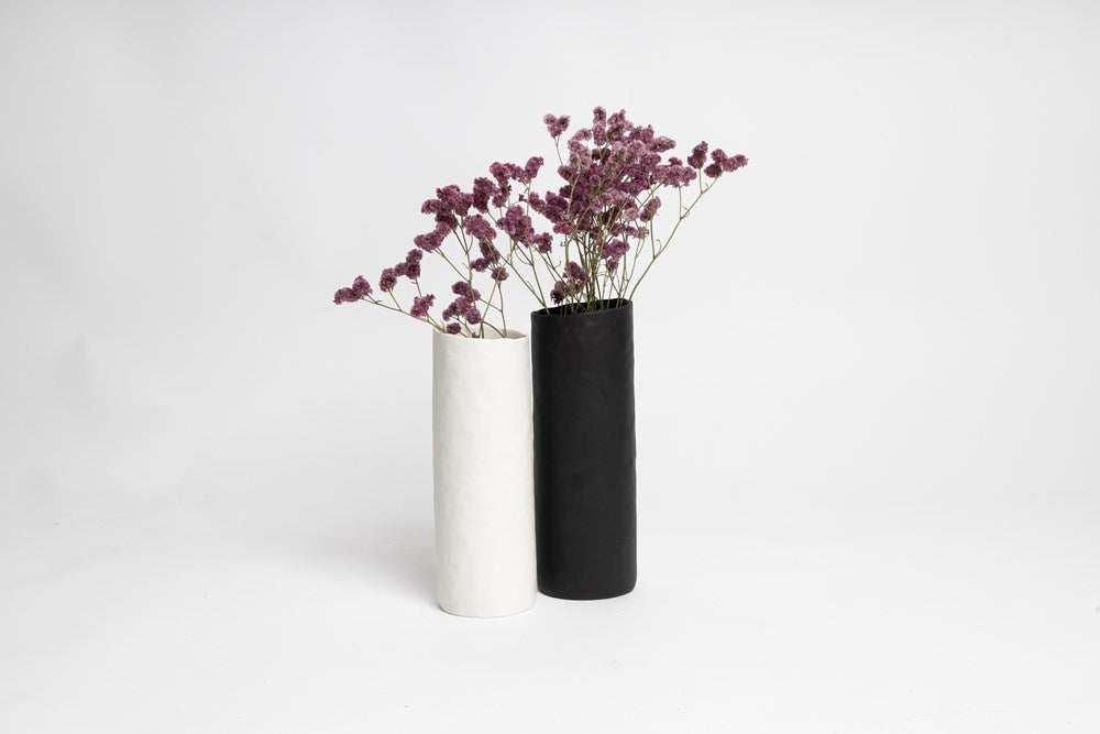 Two black and white Ned Collections Bernie Vases with purple flowers in them, featuring a matte finish.