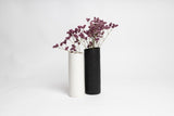 Two black and white Ned Collections Bernie Vases with purple flowers in them, featuring a matte finish.