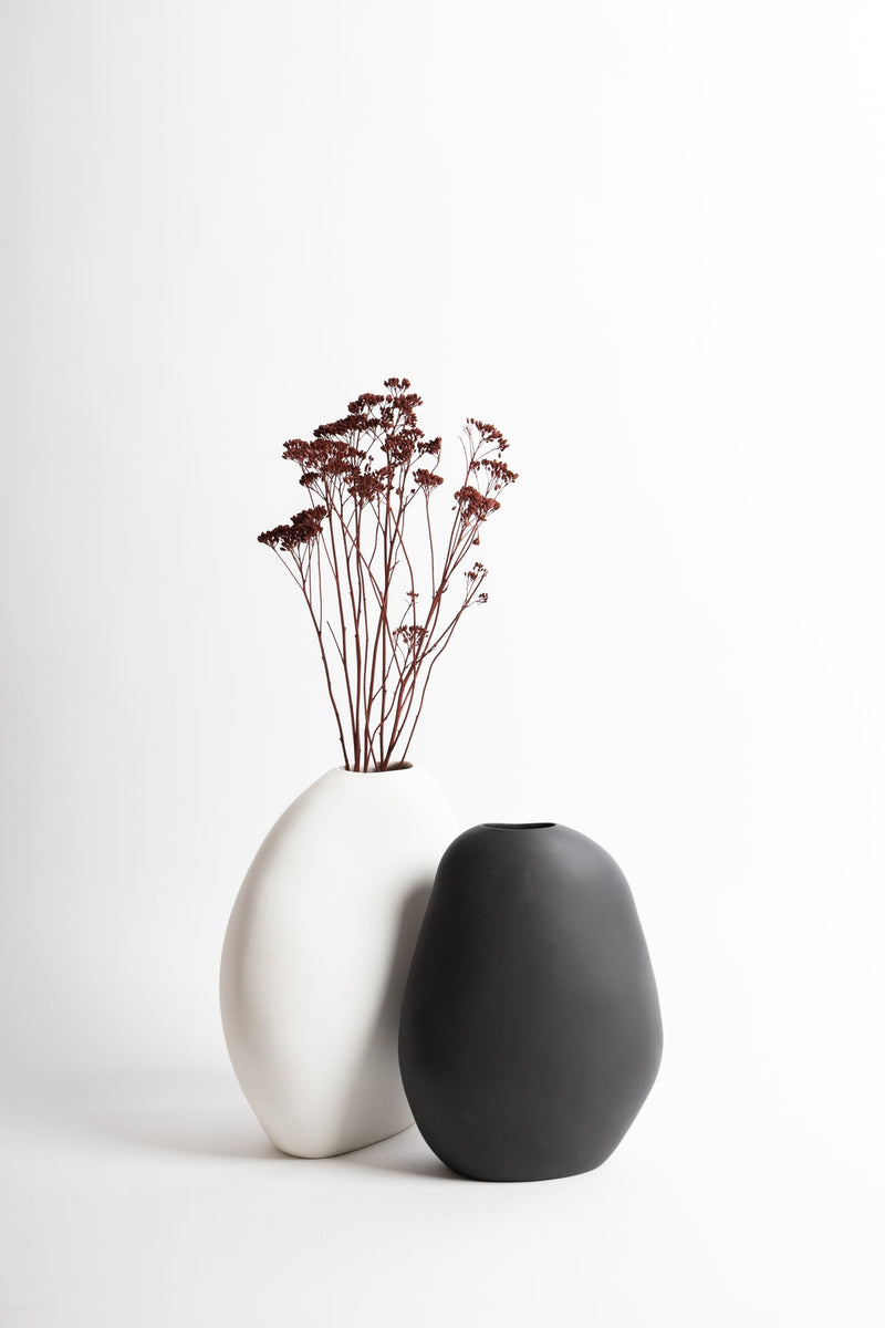 Two black and white Harmie Vases from Ned Collections on a white surface.