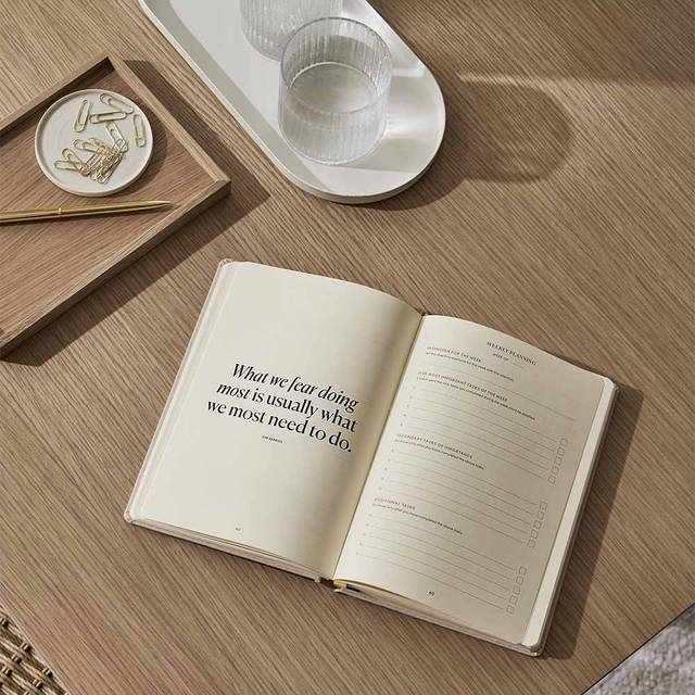 An Intelligent Change Productivity Planner is open on a table next to a glass of water.