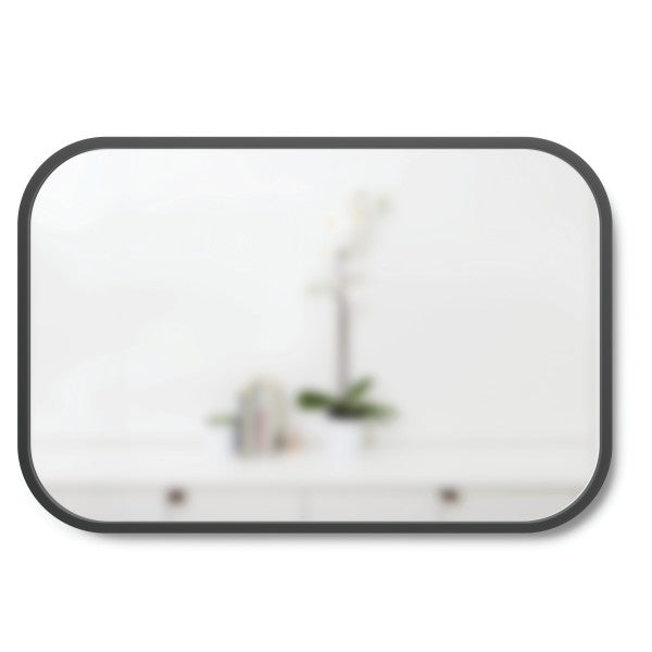 A Umbra Hub Mirror - Rectangle 61X91" Black with a plant on it.
