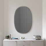 An Umbra Hub Mirror - Bevy Oval 24X36 - Smoke with a beveled oval mirror above it.