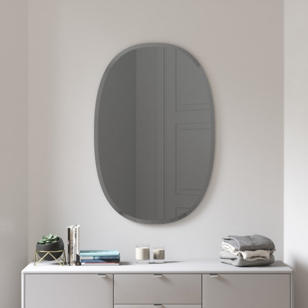 An Umbra Hub Mirror - Bevy Oval 24X36 - Smoke with a beveled oval mirror above it.