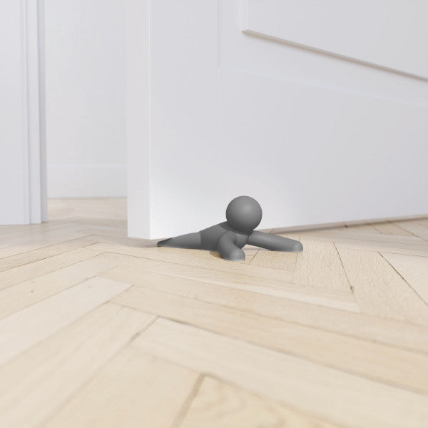 An Umbra Buddy Doorstop Charcoal is standing in front of a door.