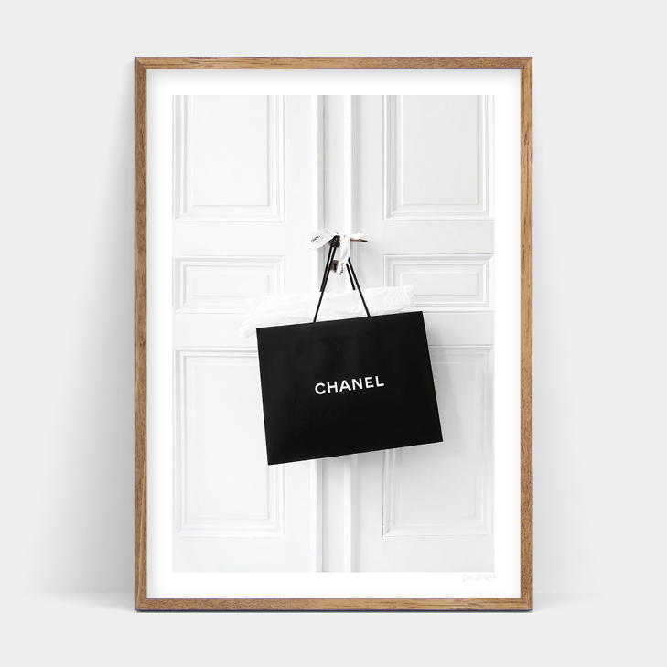 A black and white CHANEL ADDICT shopping bag hanging on a door, produced by Art Prints.