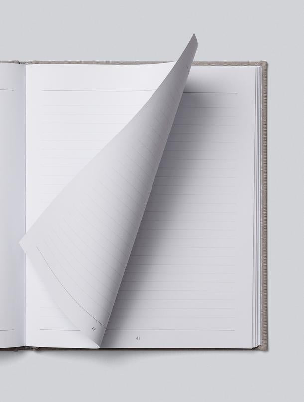 An open journal with a white cover on a grey background, capturing Write To Me's 21 Years - 21 Years Of You.
