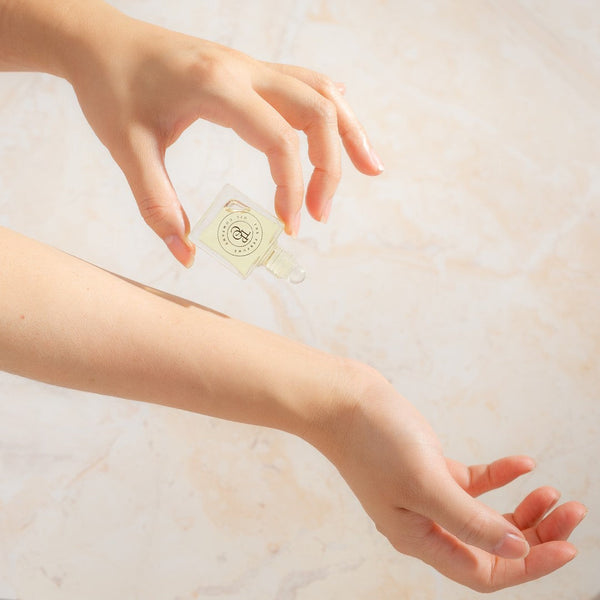 A woman's hand holding a bottle of SALT from the Designer Type Collection by The Perfume Oil Company, inspired by Wood Sage & Sea Salt (Jo Malone).