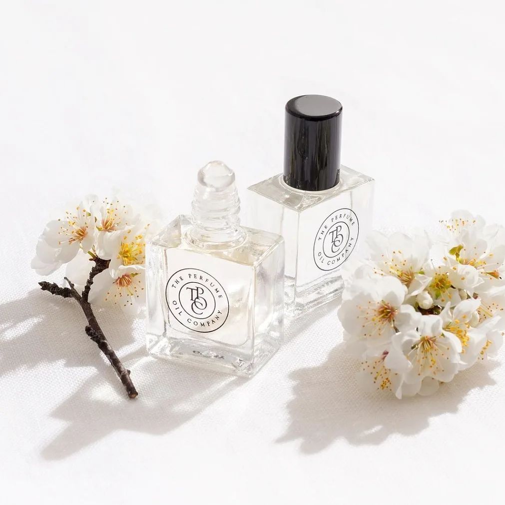 Two small bottles of NUDE, inspired by Beige (CC) perfume from The Perfume Oil Company on a white surface.