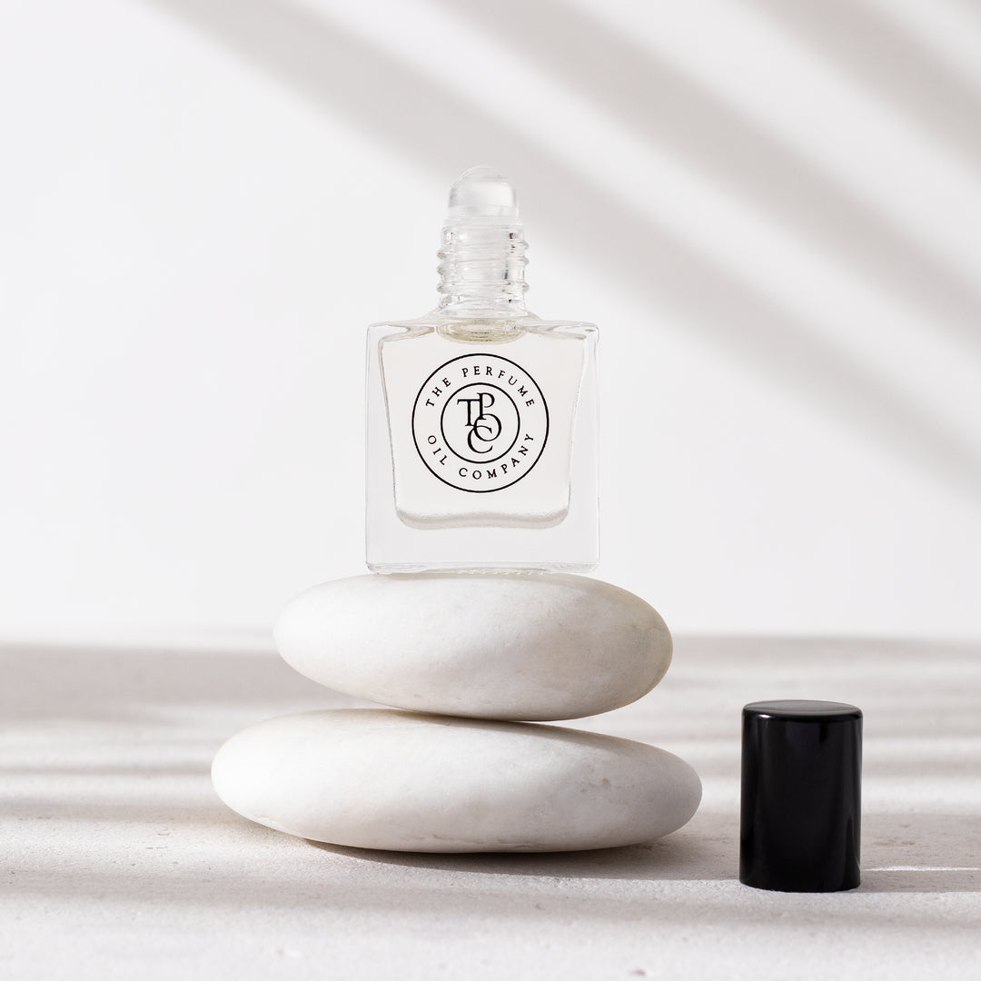 A bottle of NUDE, inspired by Beige (CC) perfume sitting on a stack of white stones, made by The Perfume Oil Company.