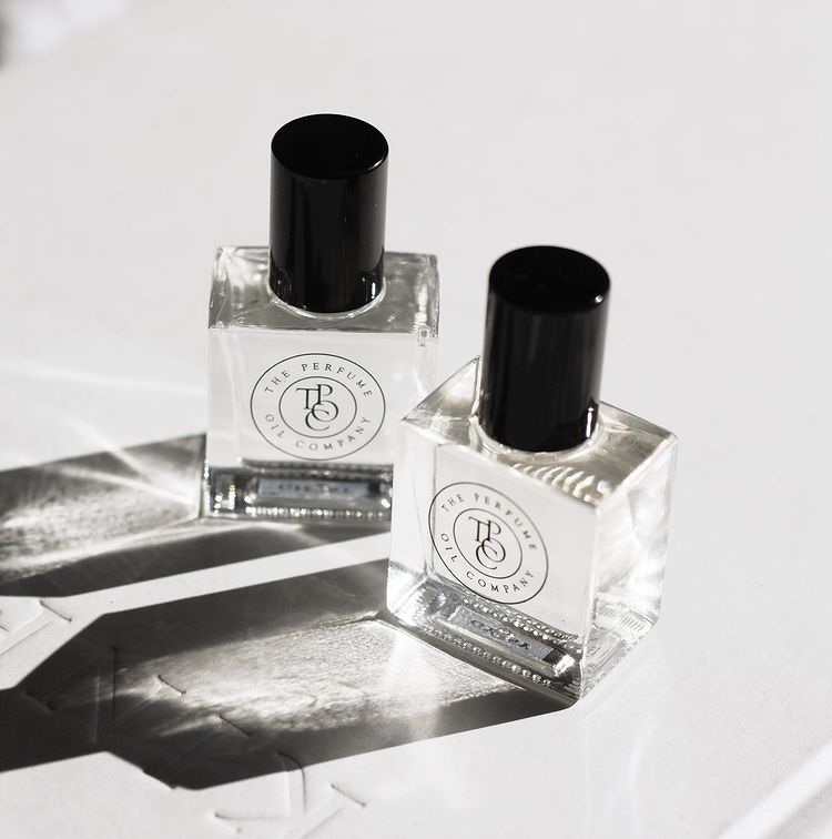 Two small bottles of NUDE, inspired by Beige (CC) perfume sitting on top of a book, from The Perfume Oil Company.