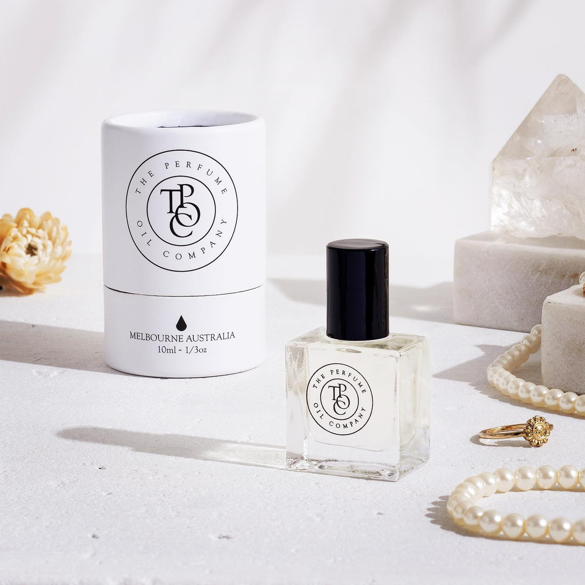 A bottle of NUDE, inspired by Beige (CC) perfume next to a necklace and pearls by The Perfume Oil Company.