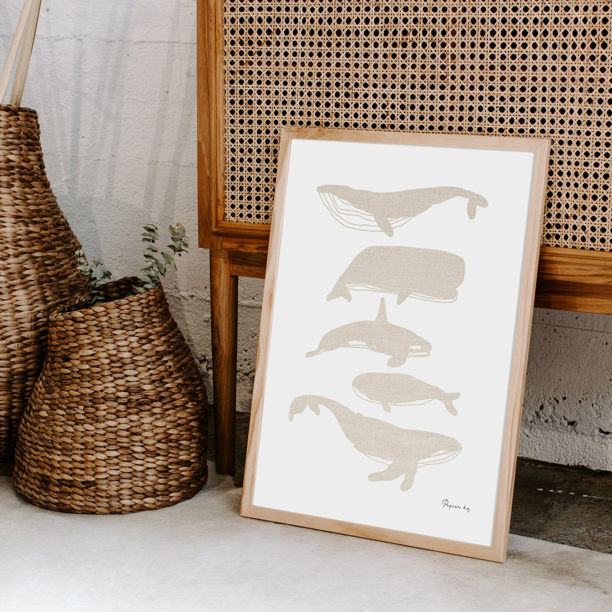 Whales print in a timber frame leaning by a cane bench and woven baskets