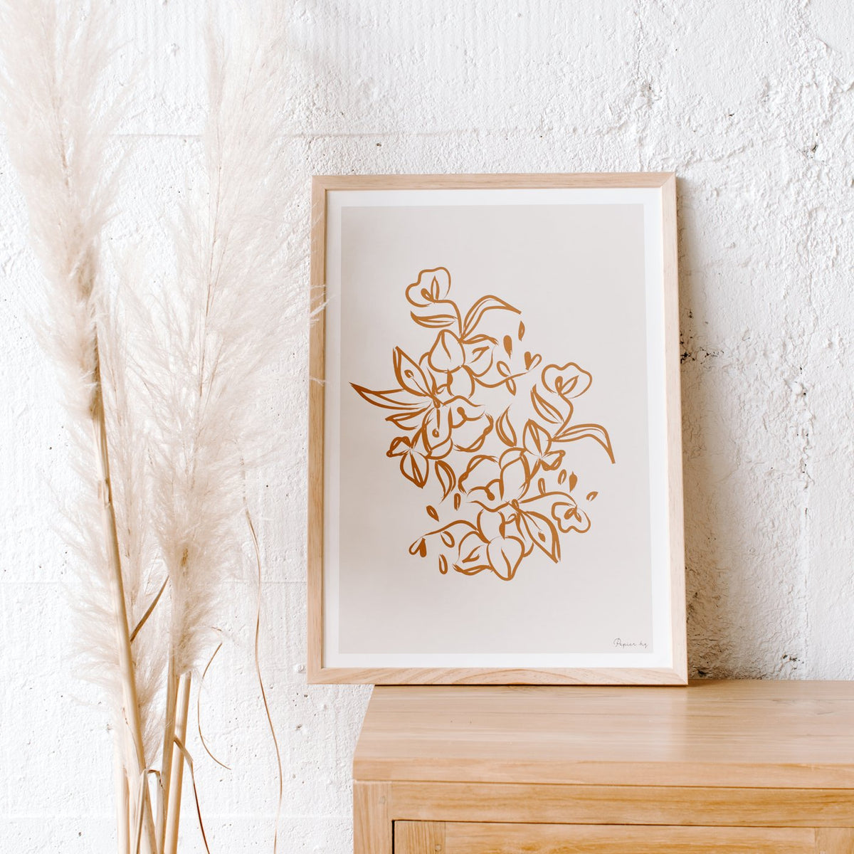 Painted Flower print in a timber frame on a sideboard beside dried pampas