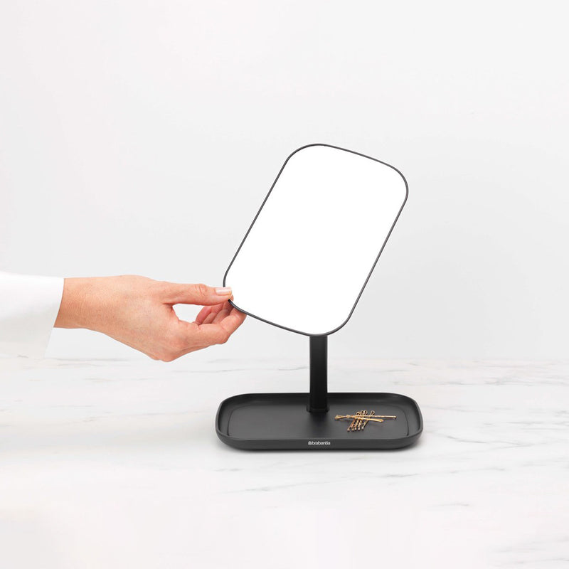 A person using a Flux Home MIRROR WITH STORAGE TRAY - Dark Grey / White as a make-up storage tray on top of a table.