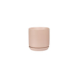 The Oslo Planter - Peach, a small pink stoneware planter by Potted, elegantly stands out against a pristine white background.