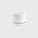 A small white Zurich Planter with a saucer on a grey background by Potted.