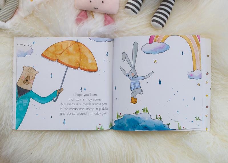 A Olive + Page children's book with the MY WISHES FOR YOU teddy bear holding an umbrella.
