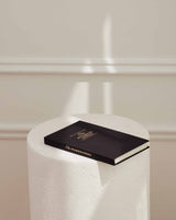 The Intelligent Change's Five Minute Journal, focused on positivity and gratitude, sits on a pedestal in front of a white wall.