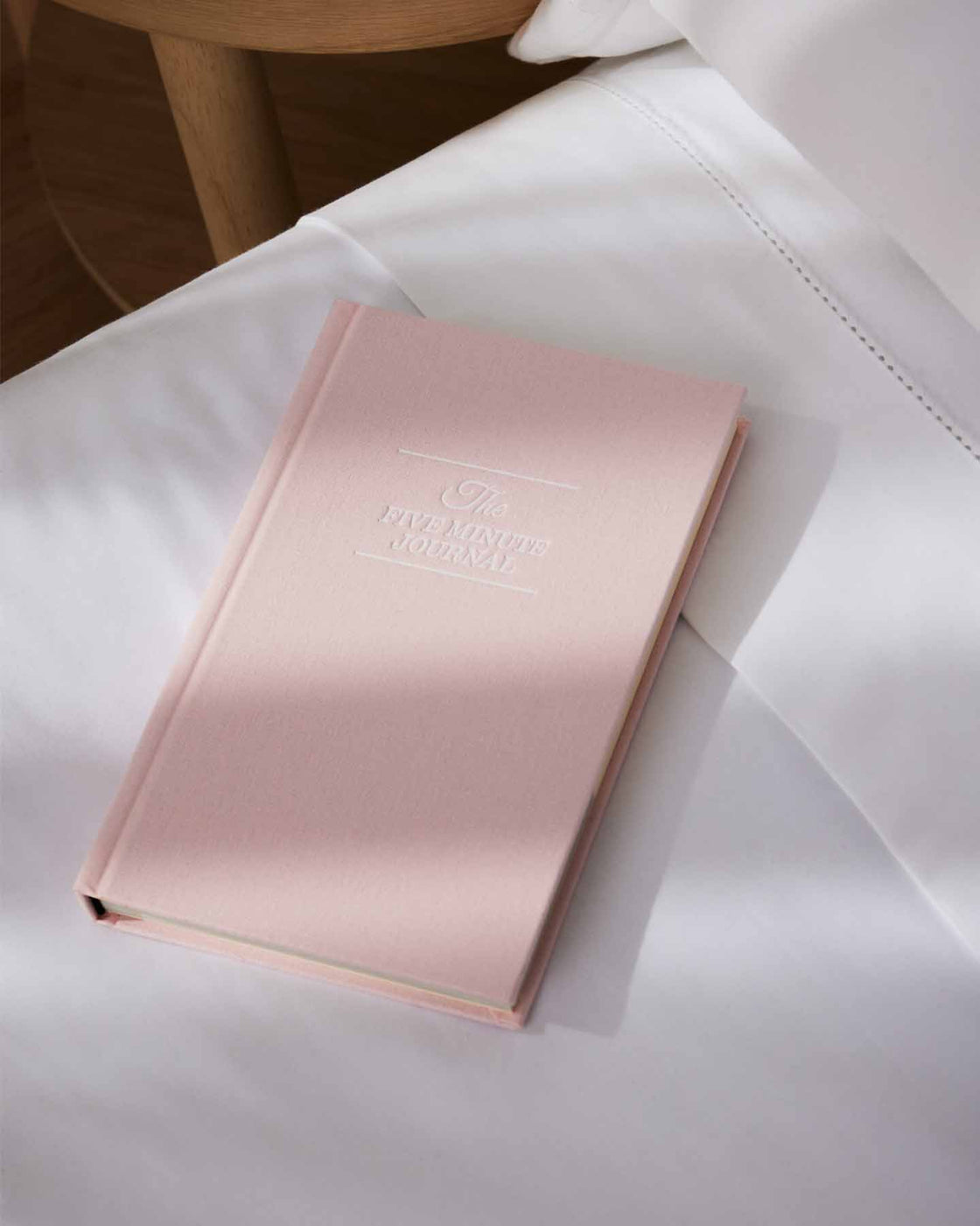 Blush pink Five Minute Journal on white bedding