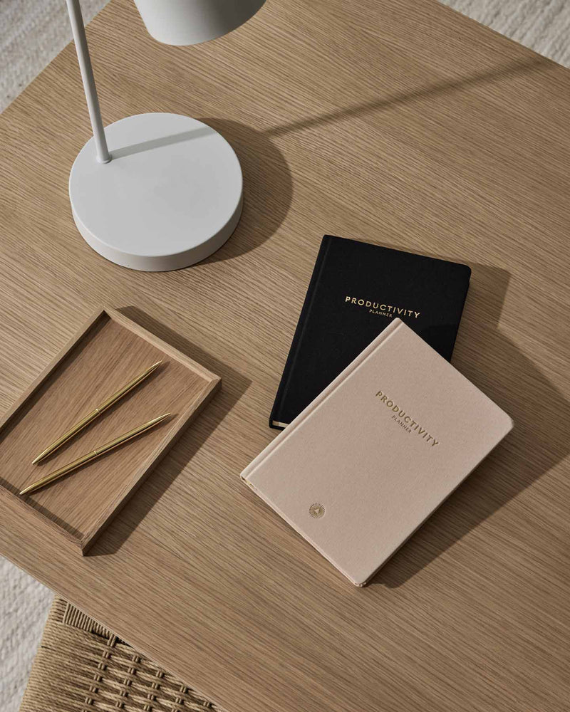 An Intelligent Change productivity planner on a wooden table next to a lamp.