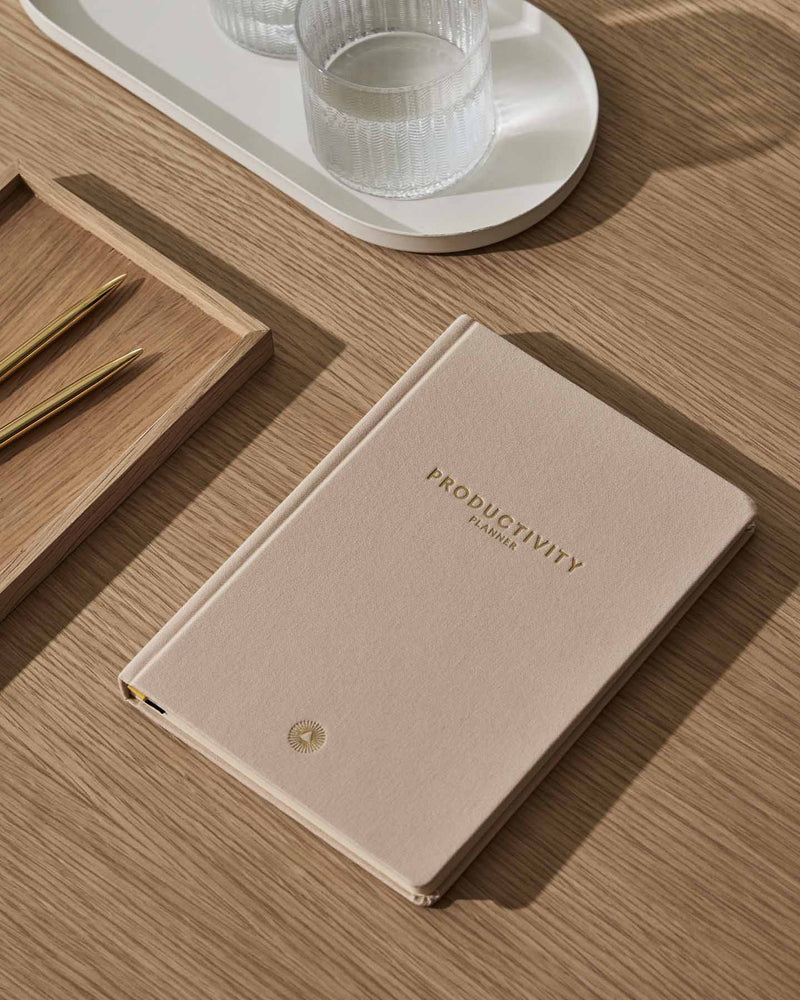 An Intelligent Change Productivity Planner notebook on a table next to a glass of water.