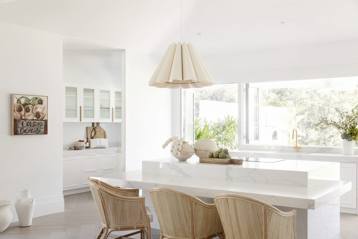 White kitchen and dining area with rattan chairs and a pendant light