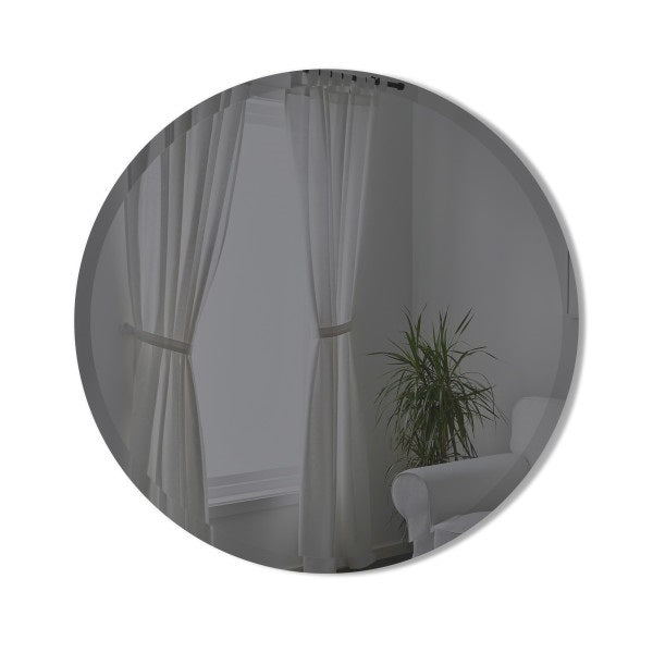 A Hub Mirror - Bevy 24inch - Smoke from the Umbra range adorns a room with elegant curtains and a lush plant.