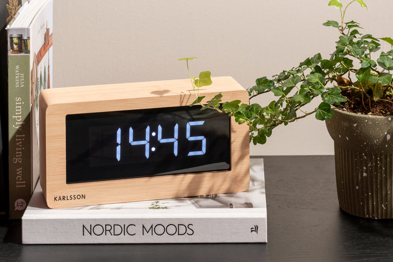 A minimal Karlsson LED clock with a plant.