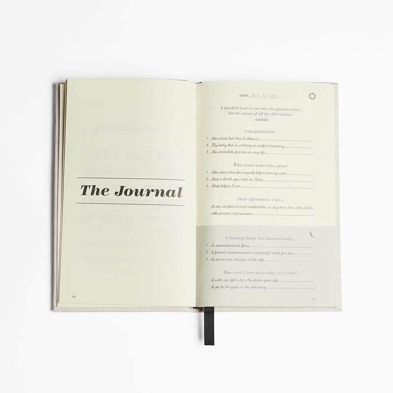 Five Minute Journal open at a quote page and a daily page, ribbon marker hanging
