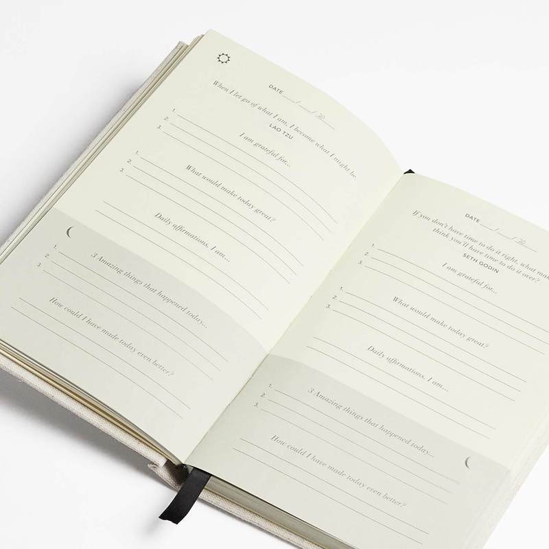 Five Minute Journal open at an angle to its prompt pages