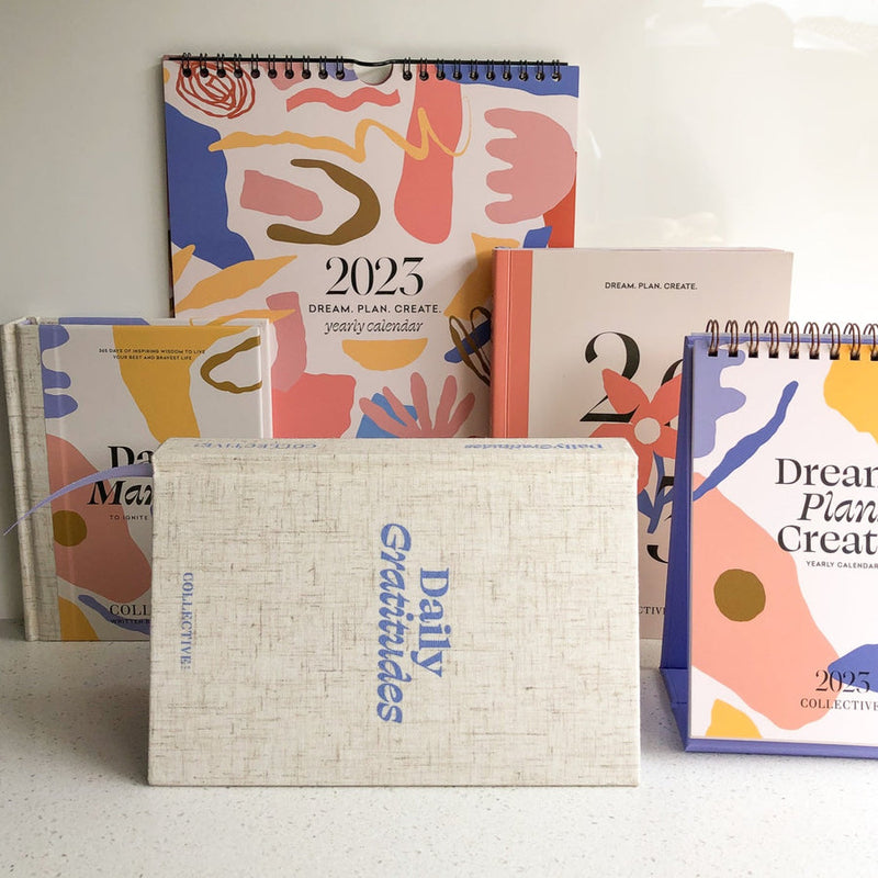 A set of Daily Gratitudes Version 2 journals and wellness calendars by Collective Hub on a table.