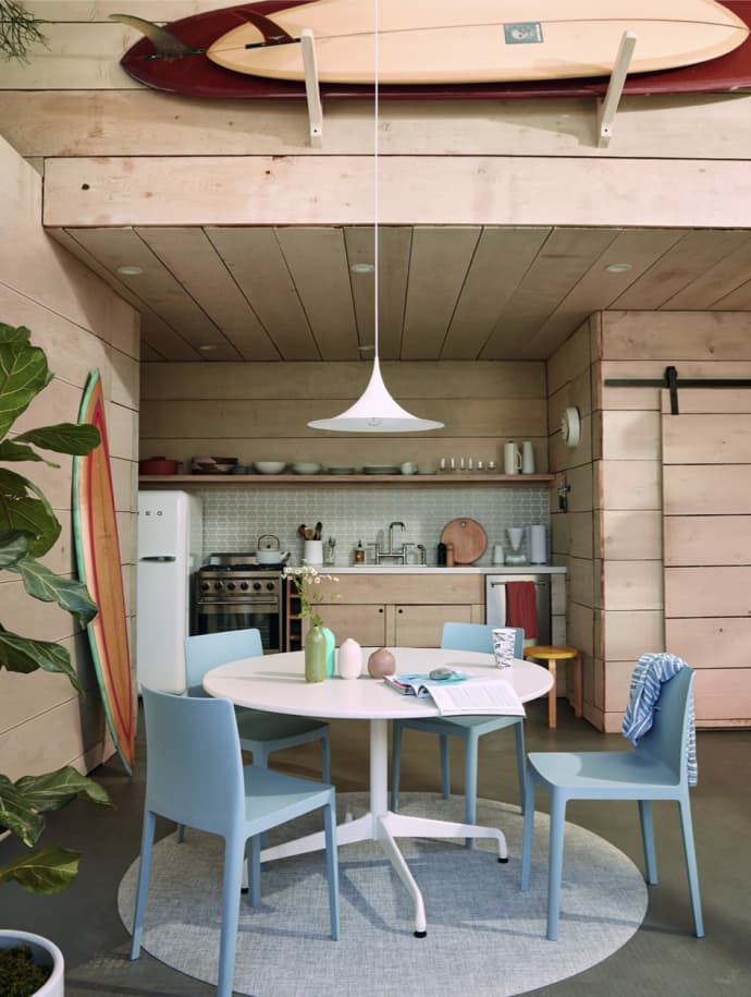 Photo from the book of a kitchen with blue chairs and a surfboard on the ceiling