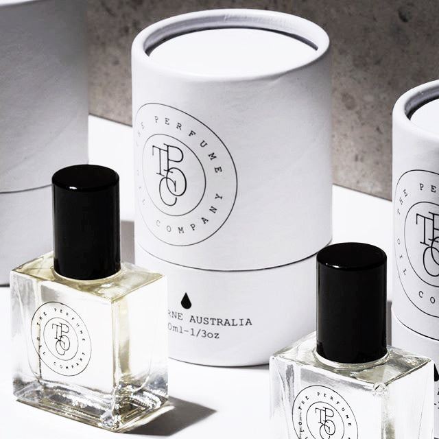 Close view of perfume oil bottles in front of white gift tubes