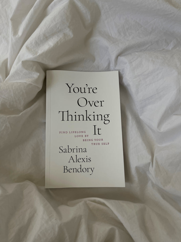 Front cover of the book on white bedding