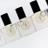 Five bottles of SASS, inspired by Black Opium (YSL) roll-on perfume oils are lined up on a white surface.