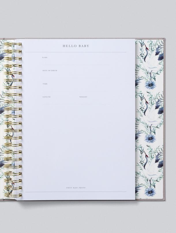 A linen bound BABY | YOUR FIRST FIVE YEARS notebook with a floral pattern on it, made by Write To Me.