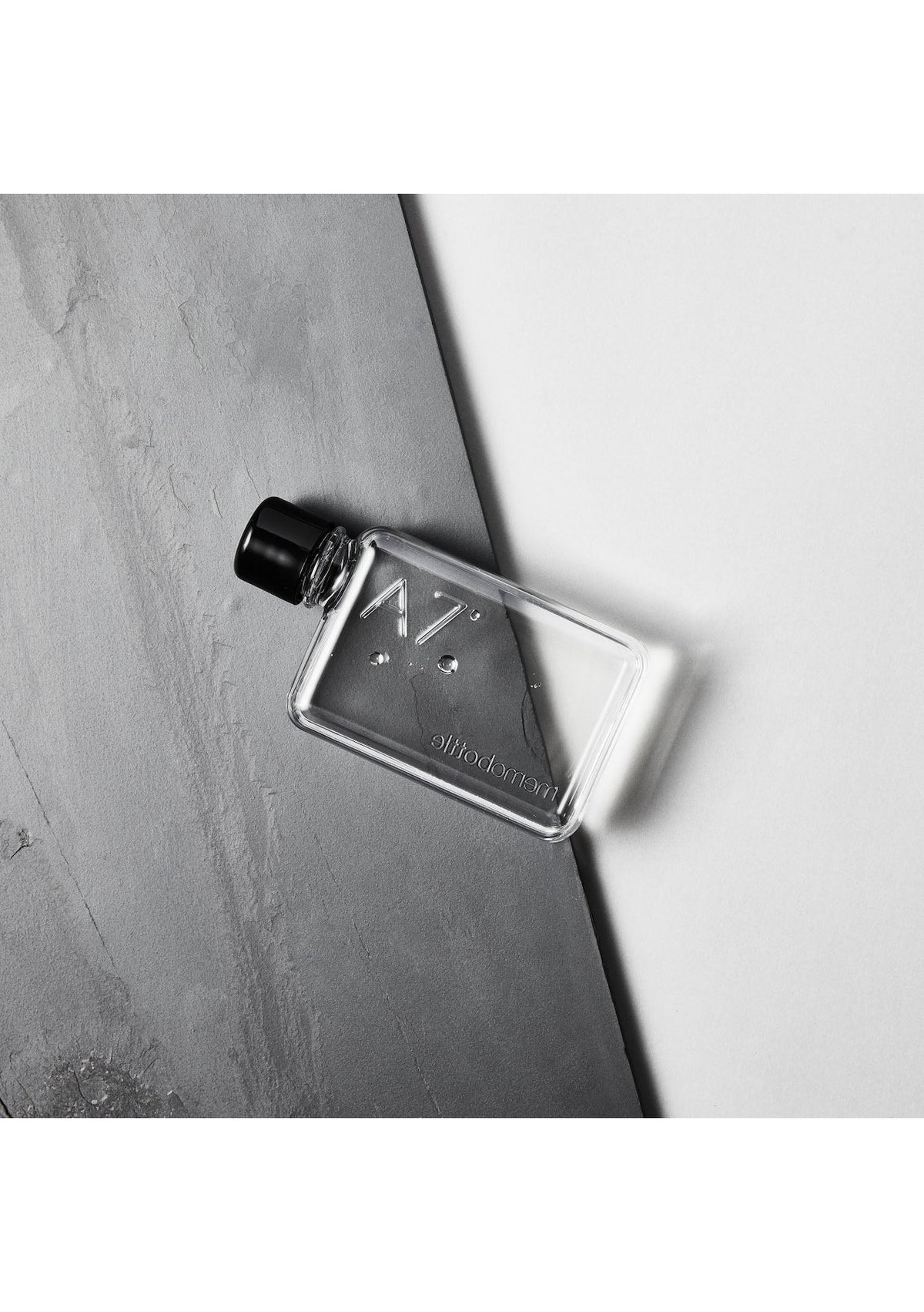An MemoBottle A7 memobottle, compact and sleek, filled with eau de toilette, resting on a grey surface.